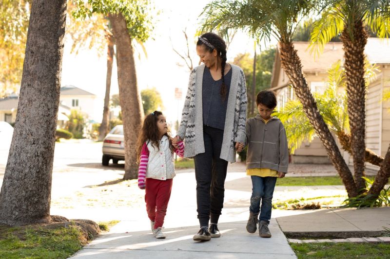 mom and 2 children walking down sidewalk